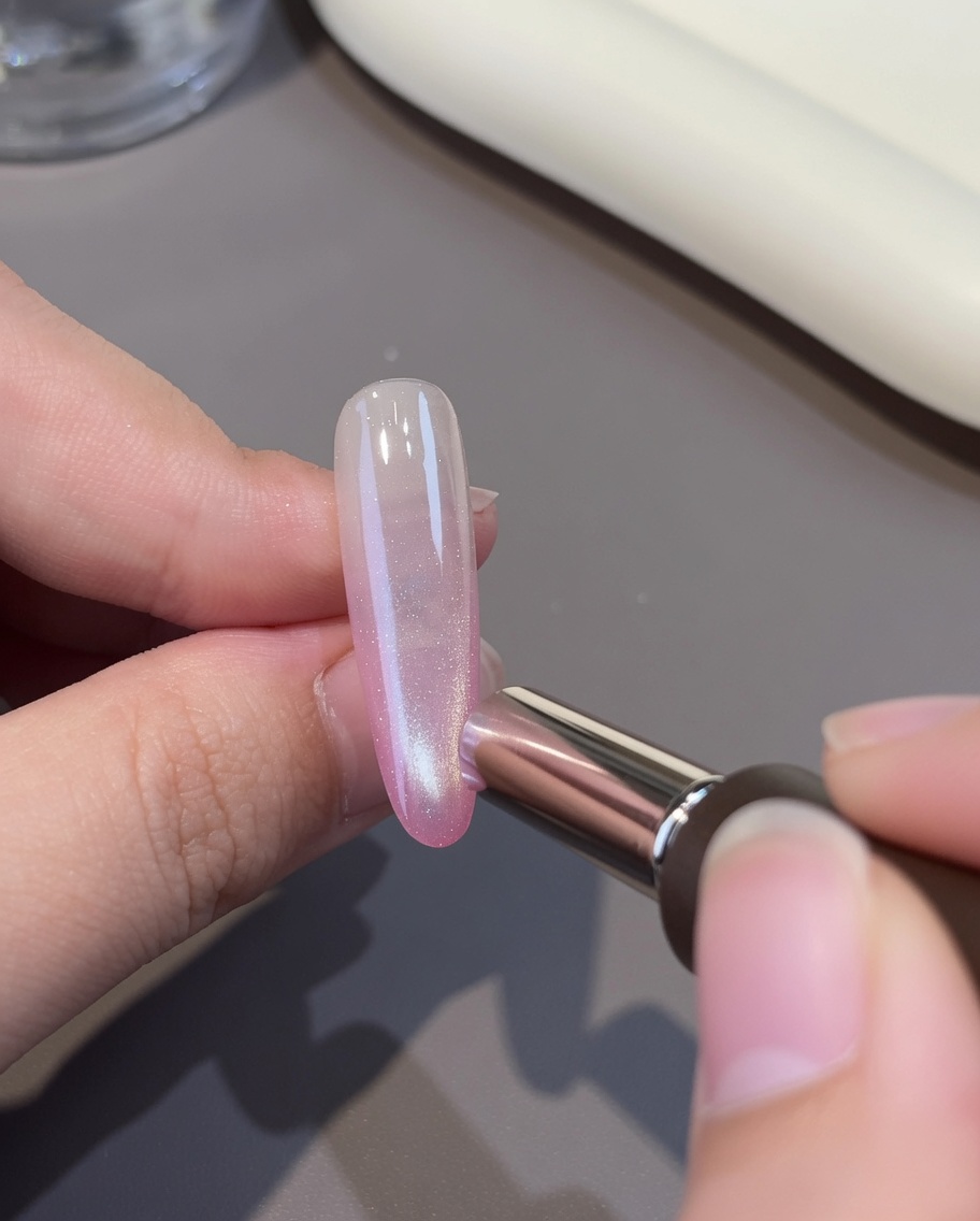 Uno strato di gel cat-eye bianco applicato sopra la base rosa.
