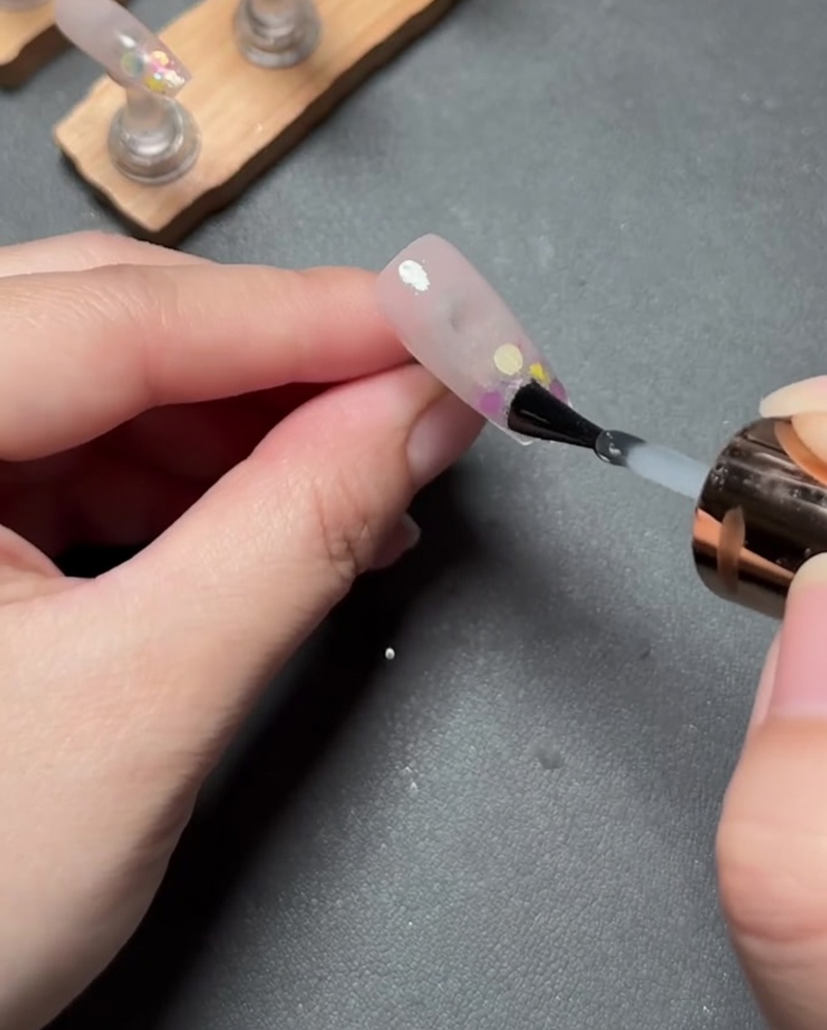 Un sottile strato di gel trasparente applicato sullunghia con sfumatura rosa e glitter finita.