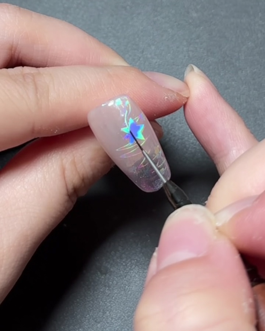 Un pennello di dettaglio che dipinge gel colorato vivace allinterno di un design a stella su ununghia.