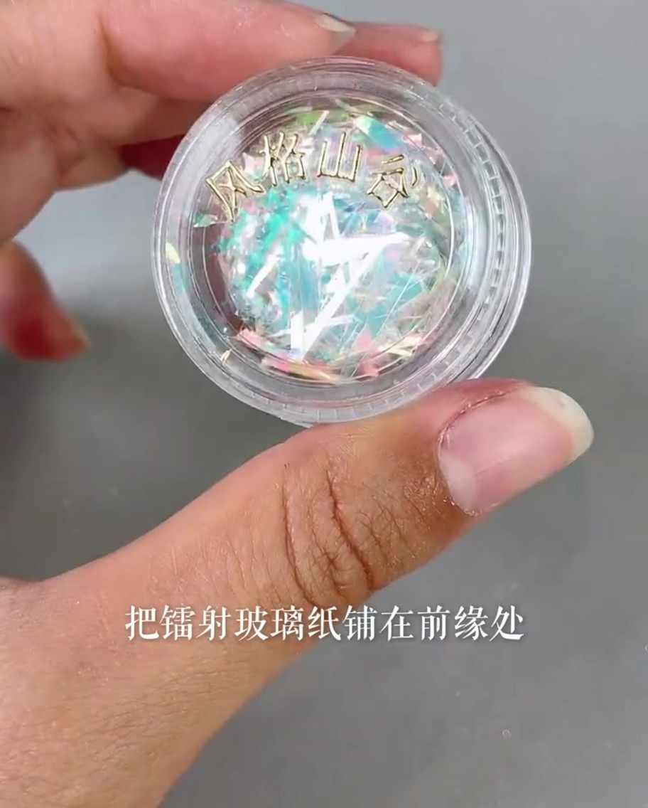 Piccoli pezzi di carta vetro laser iridescente applicati sul bordo di una tip con uno strumento di precisione.