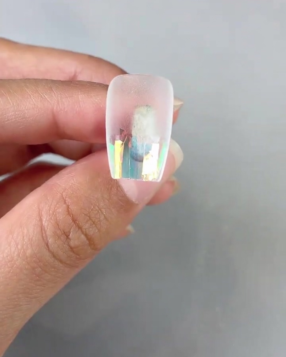 Un pennello applica uno strato di gel top coat trasparente sopra la carta vetro laser sulla tip.