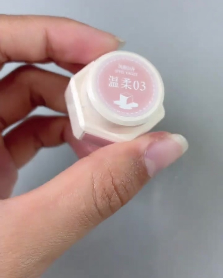 Un pennello applica uno strato di smalto gel rosa sulla base della tip.
