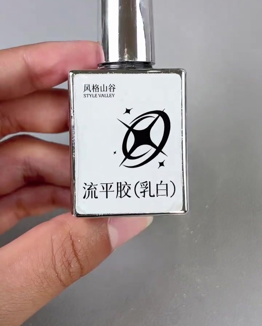 Un piccolo pennello applica una goccia di gel bianco lattiginoso nellangolo di ununghia decorata.
