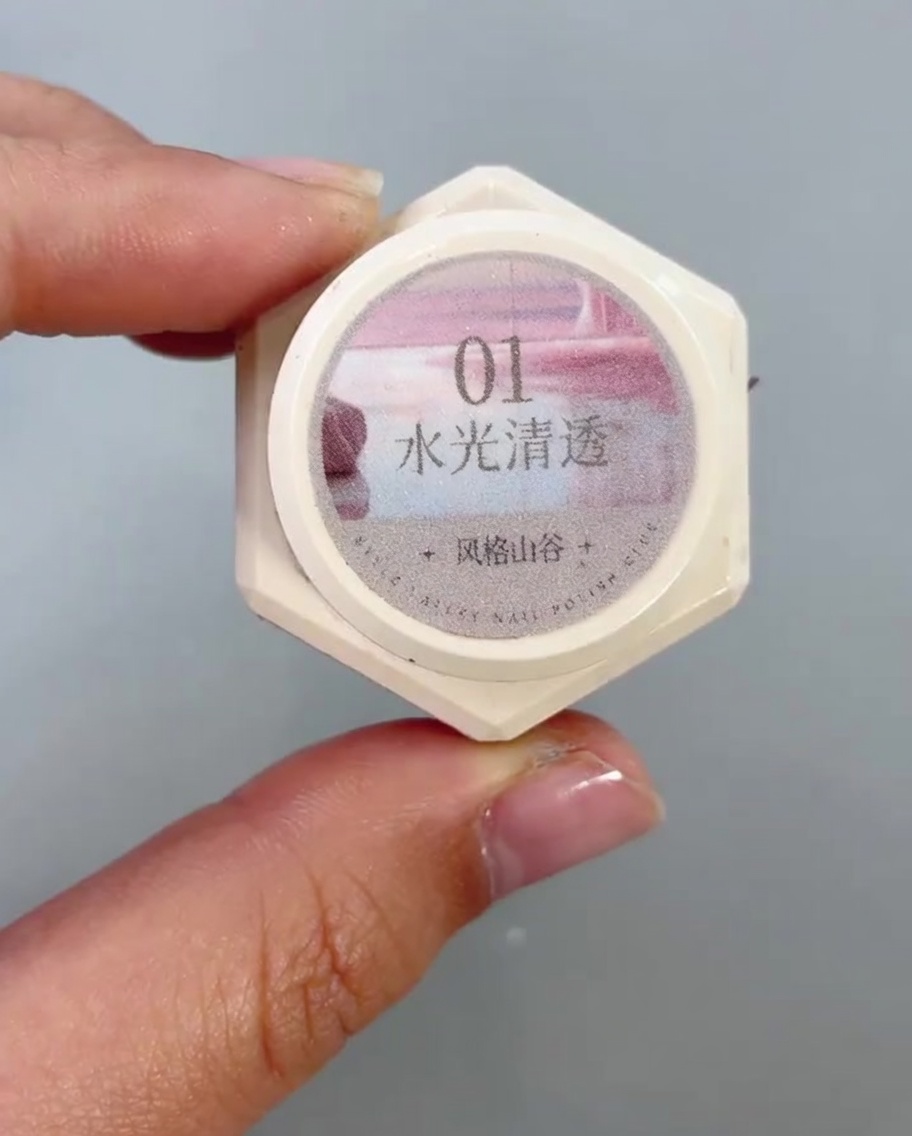 Un pennello per unghie applica un gel cat-eye trasparente e brillante sulla metà inferiore di ununghia.