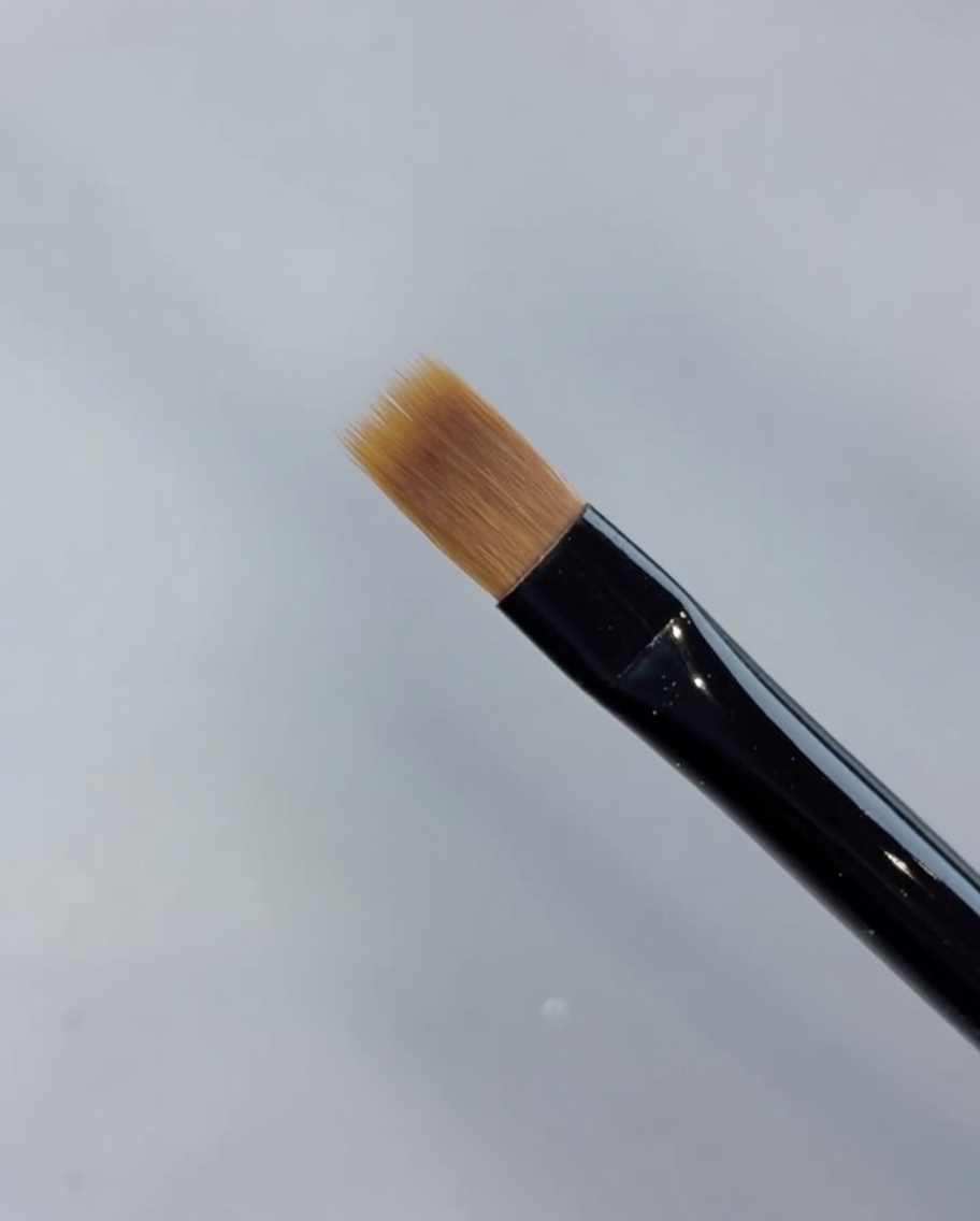 Primo piano di un pennello da sfumatura che tira in avanti lo smalto gel per creare un gradiente.
