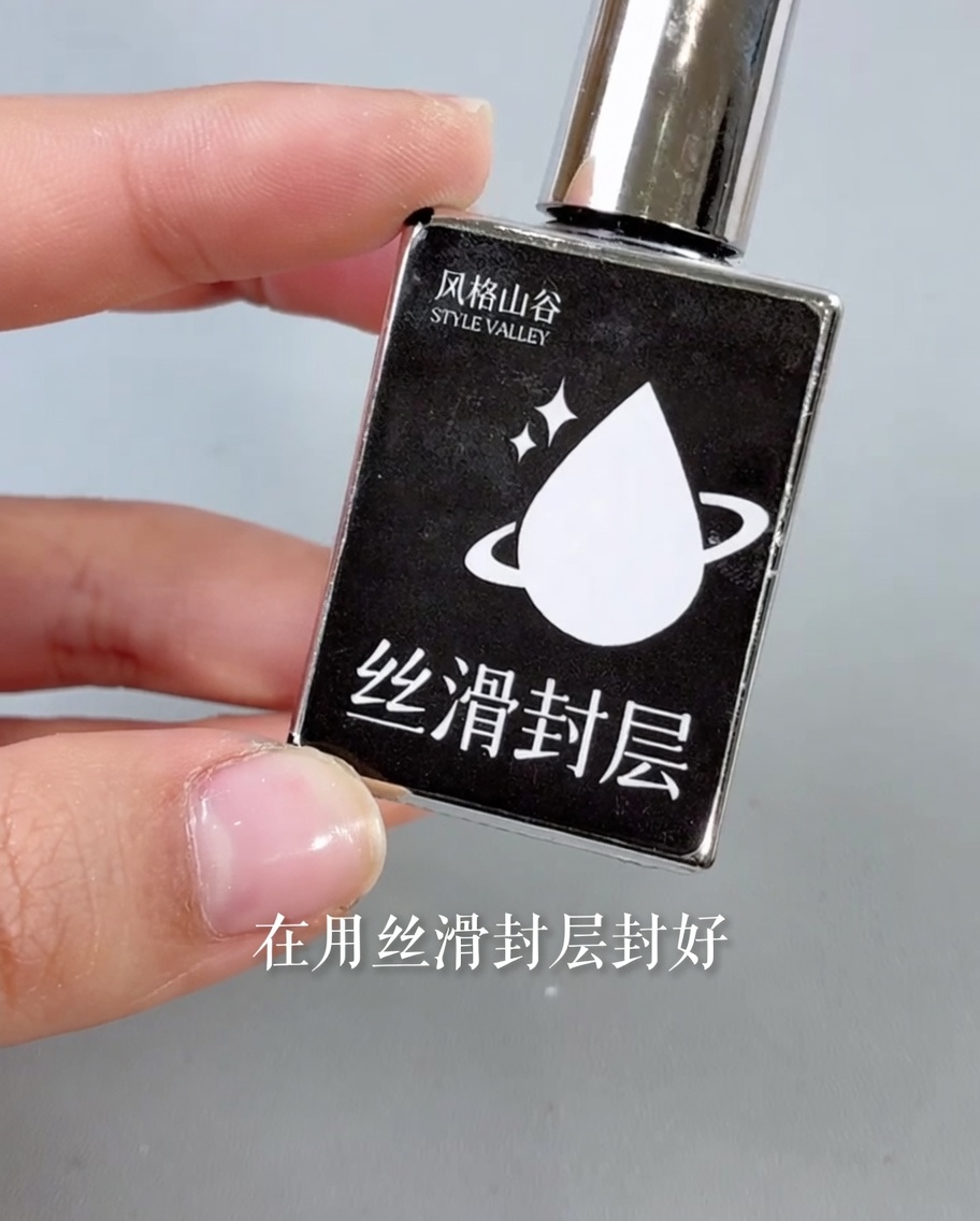 Un pennello applica un top coat trasparente e lucido sopra il design finito di ununghia.