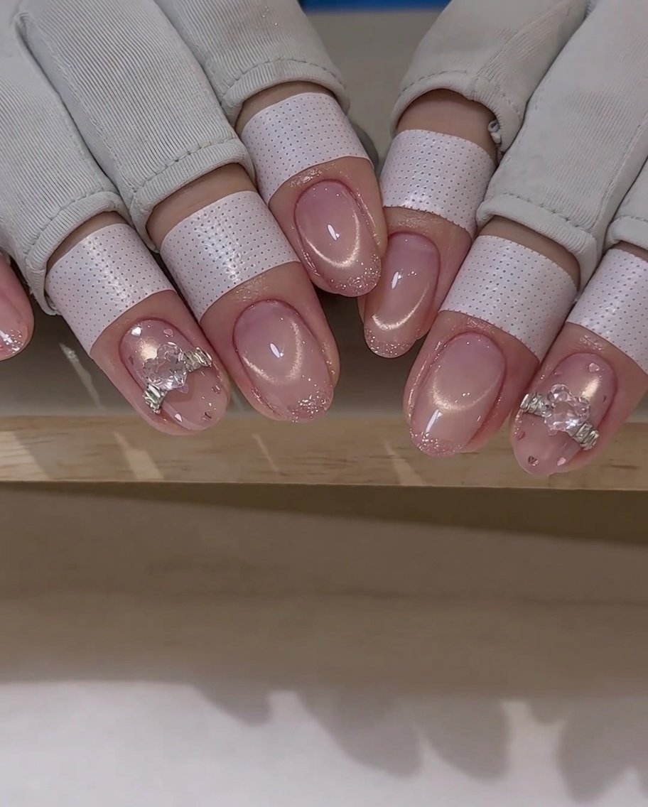 Un pennello da nail art applica uno strato sottile di top coat attorno a un charm a cristallo su ununghia.