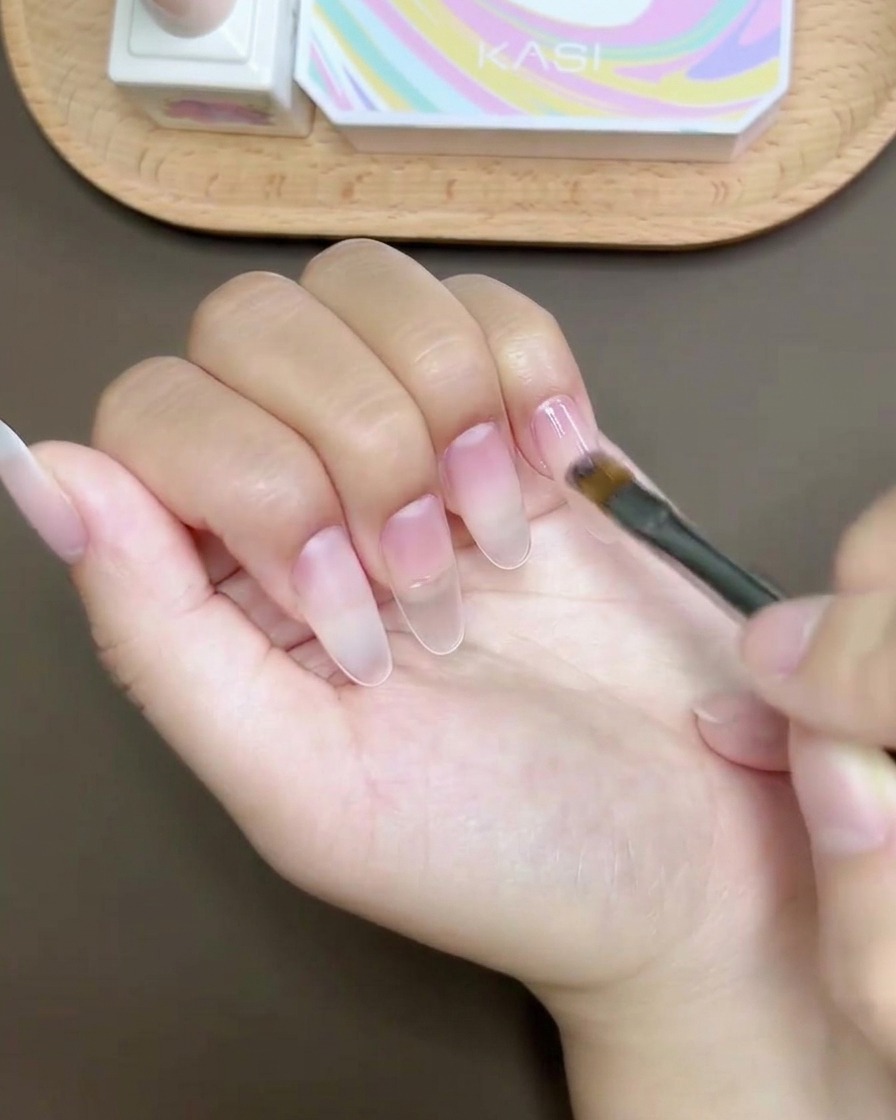 Un pennello per gel applica un top coat liscio e lucido sopra il design dellunghia completato.