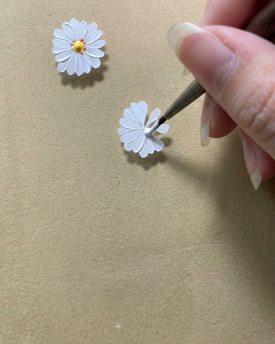 Un pennello di precisione che perfeziona i bordi interni dei petali bianchi per lasciare uno spazio circolare al centro.