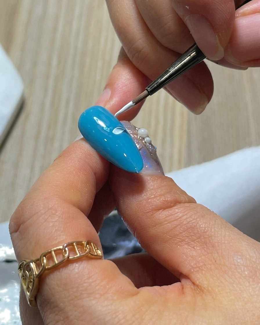 Ununghia blu con due petali di gel bianco dipinti fianco a fianco usando la tecnica di pressione e rilascio.
