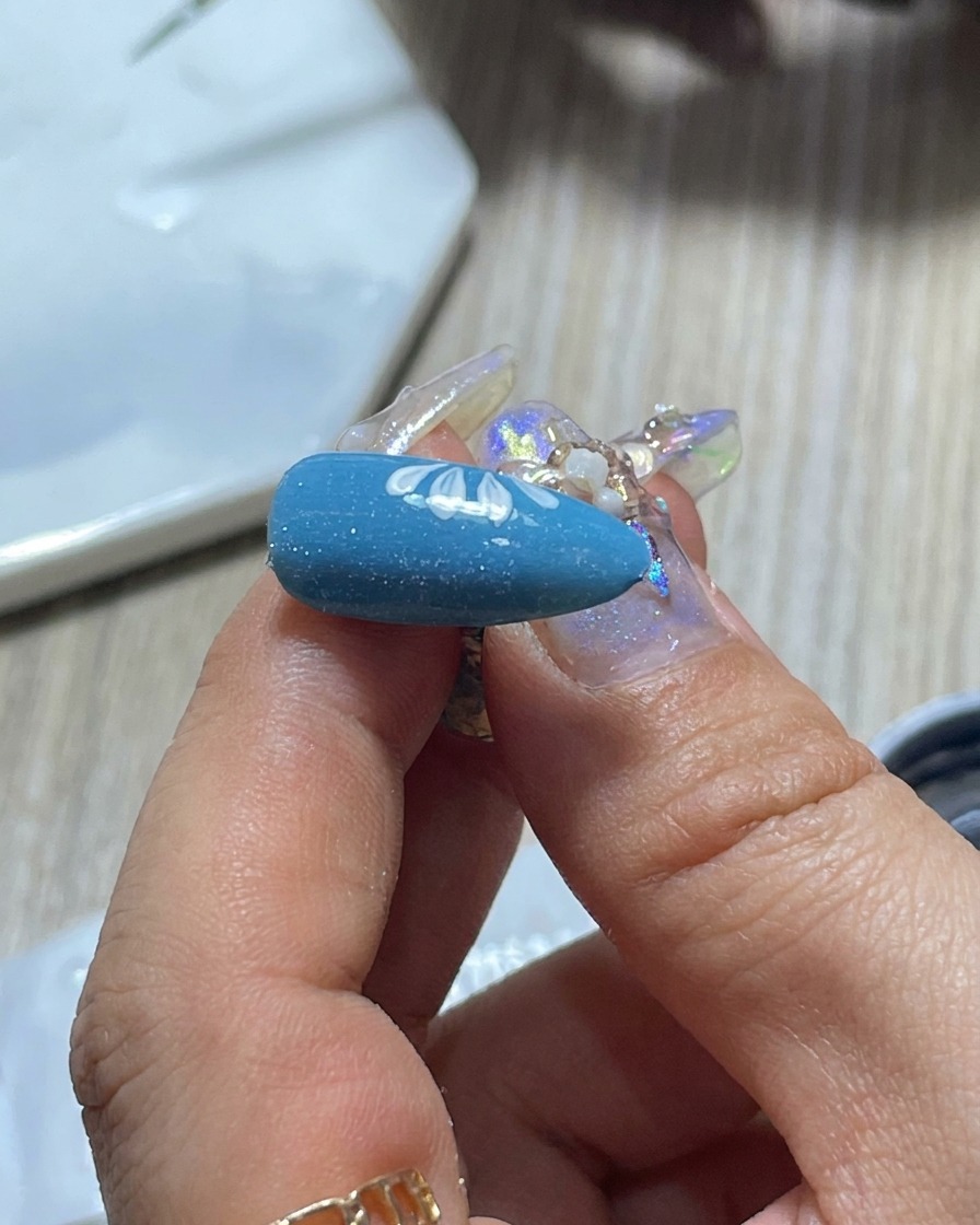 Dettaglio di un pennello per nail art che viene pulito su una tavolozza per controllare la quantità di smalto gel bianco.