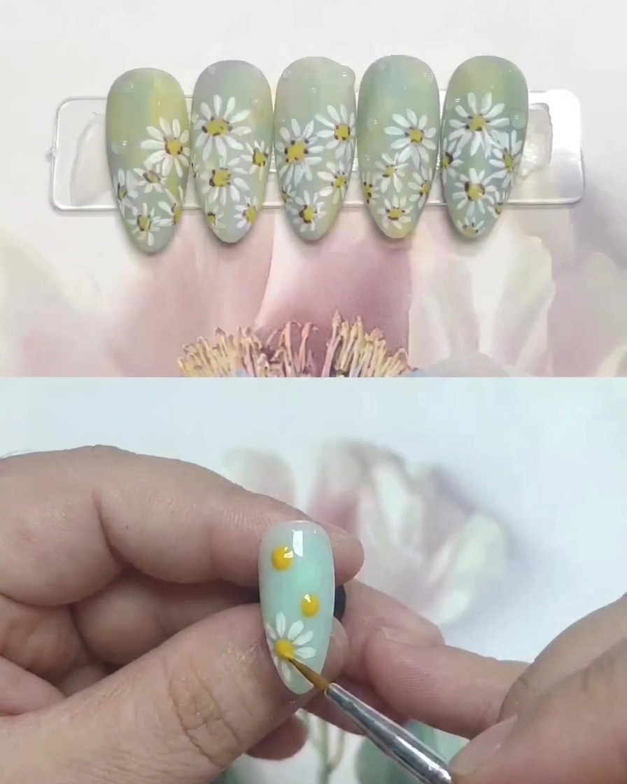 Un pennello che applica un top coat opaco sopra una nail art con margherite completata.