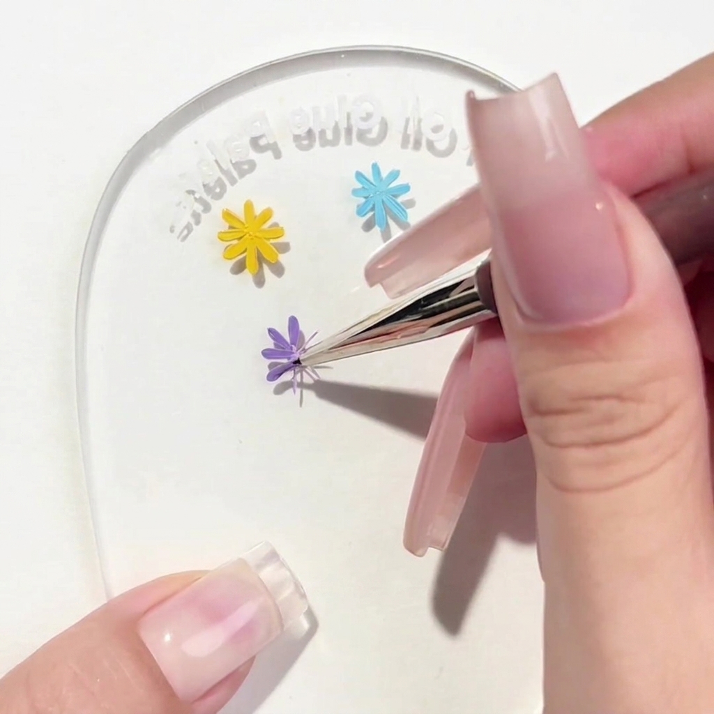 Un pennello liner che applica un terzo petalo viola al design della margherita sulla tavolozza.