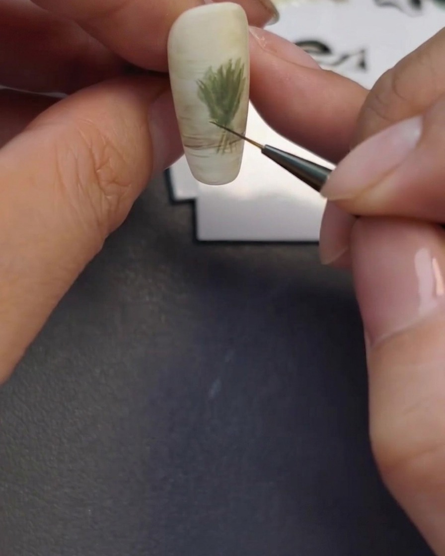 Un pennello liner sottile che crea il contorno leggero di un vaso di vetro alla base del design dellunghia.