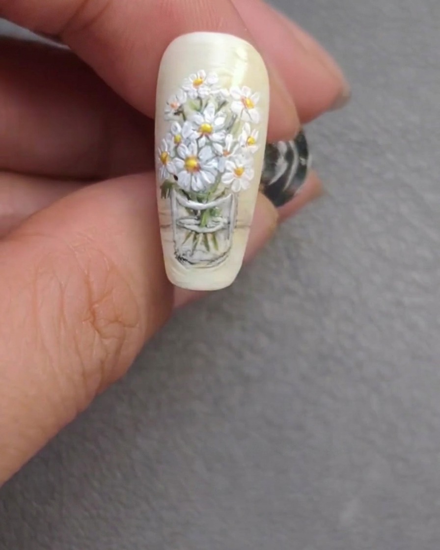 Il design finale della nail art con bouquet di margherite, che mostra steli rifiniti e luminosi riflessi floreali.