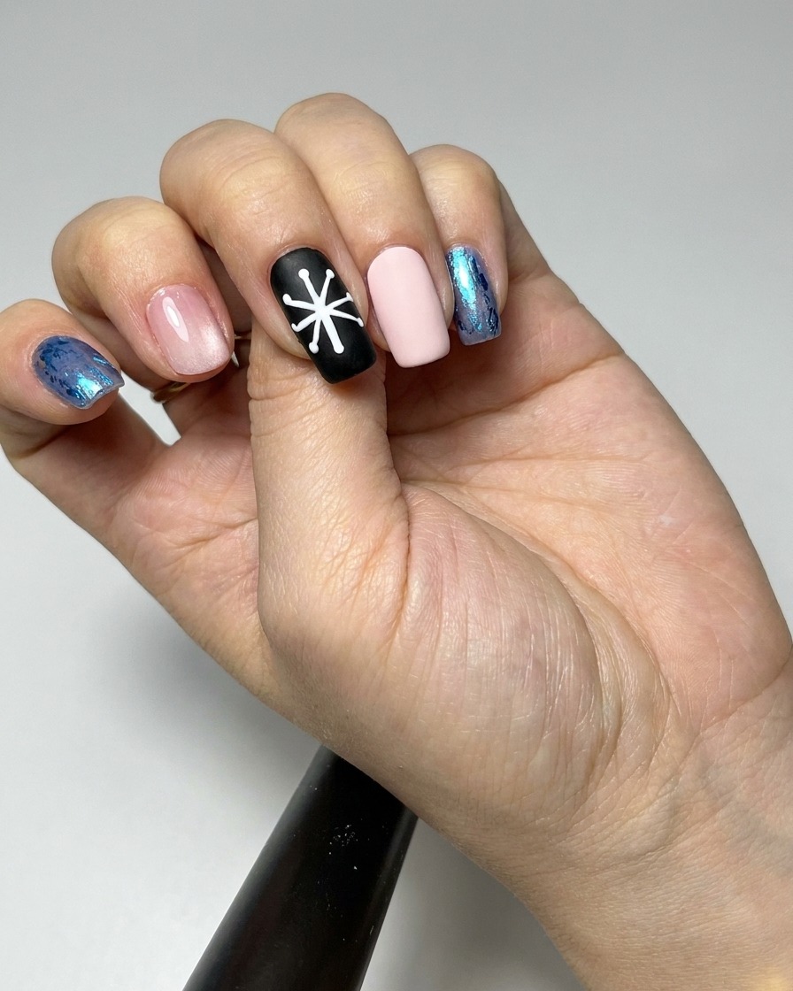 Un pennello liner che riempie le sezioni dei petali di un design a margherita su ununghia nera con gel bianco.