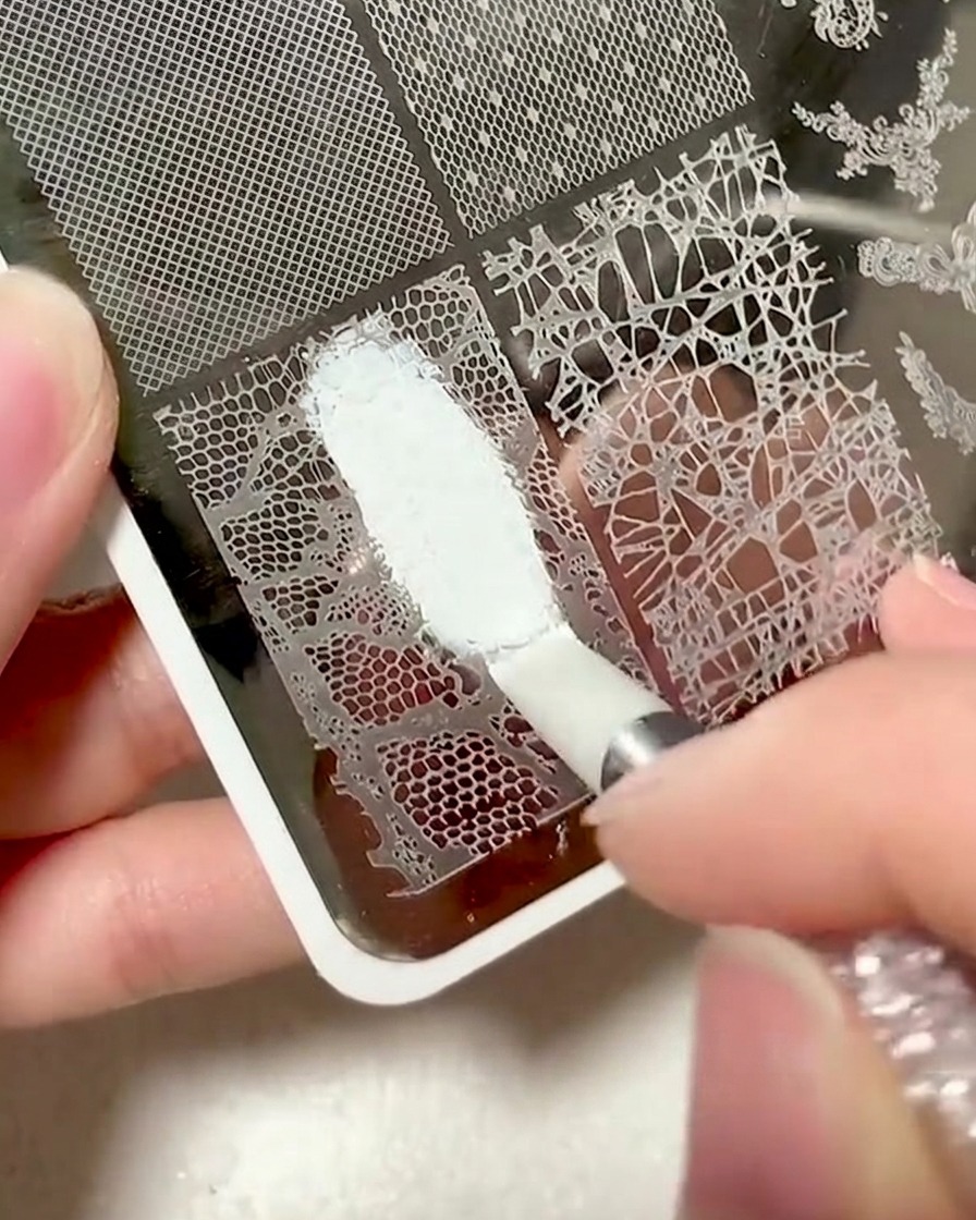 Una spatola in plastica viene usata per pulire il gel in eccesso da una piastra per stamping.