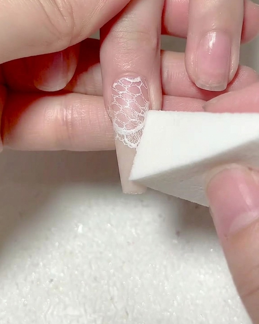 Una spugnetta che picchietta un secondo strato di gel bianco sulla punta dellunghia.