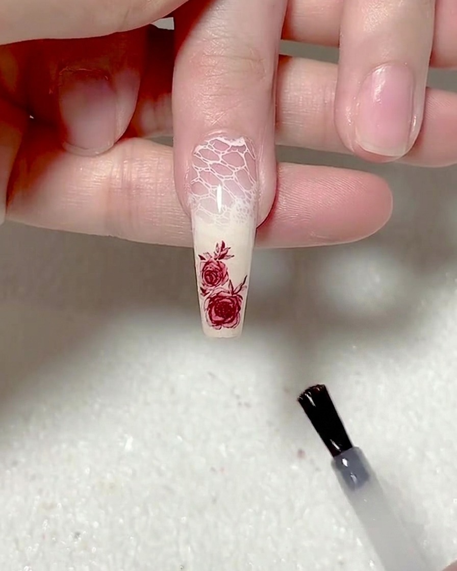 Un pennello applica uno strato uniforme di top coat opaco sullunghia.