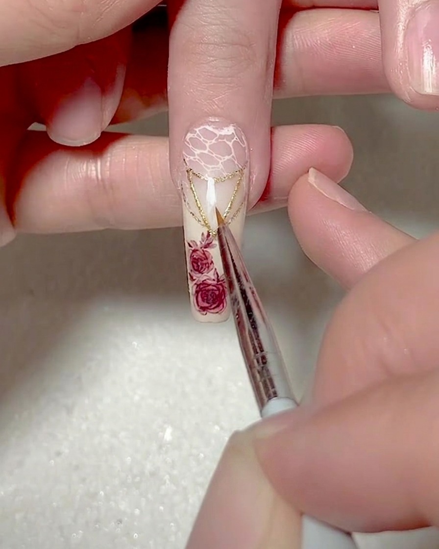 Primo piano di un pennello liner fine che dipinge un piccolo e preciso triangolo di gel bianco sulla punta dellunghia.