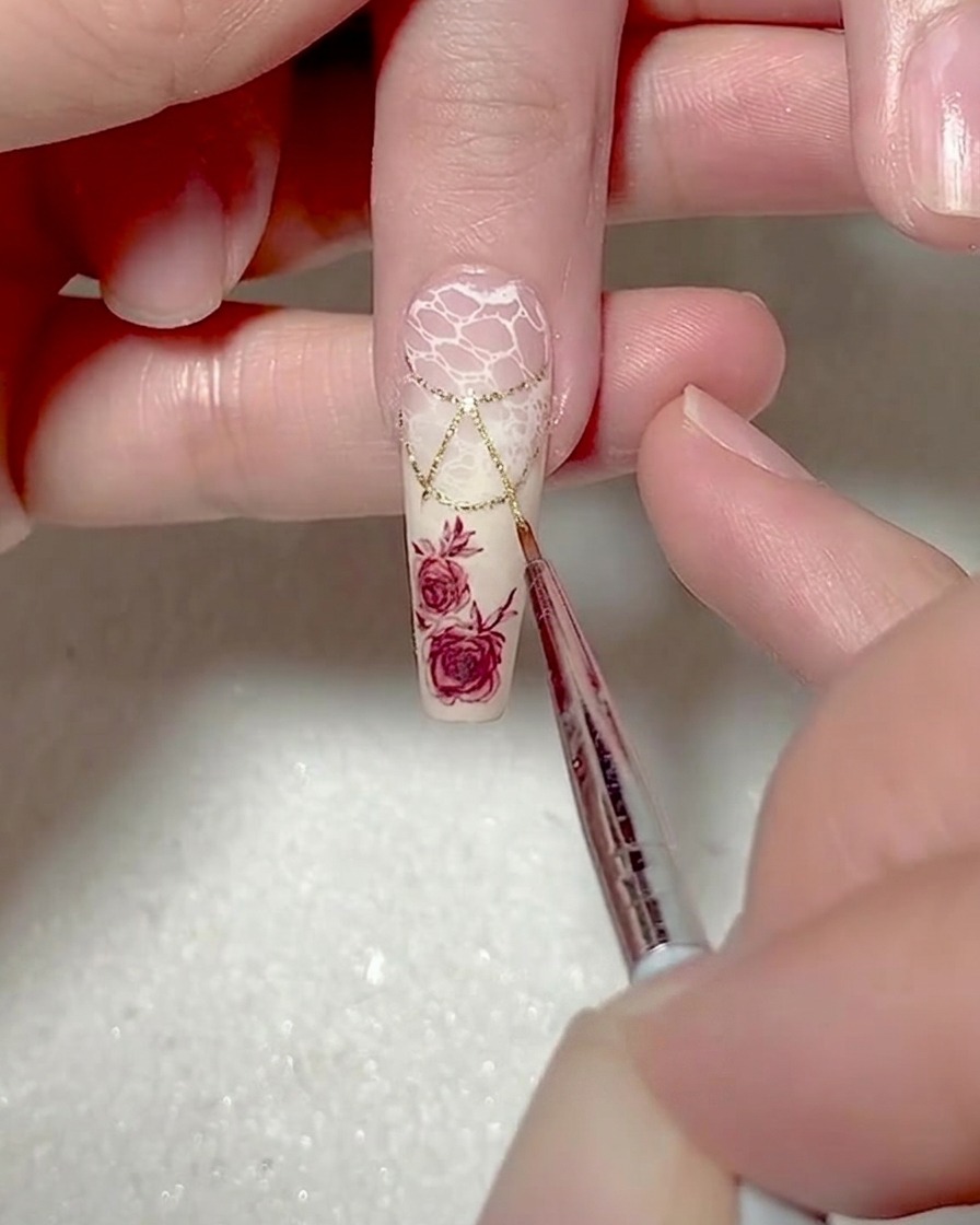 Primo piano di un pennello liner fine che aggiunge contorni in gel bianco lungo i lati di un design triangolare.