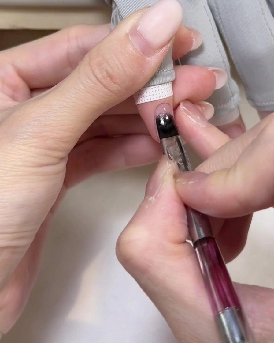 Una mano inserita in una lampada UV per polimerizzare la base gel.