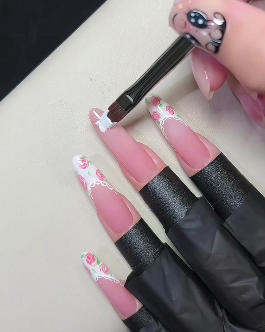 Un pennello piatto per gel applica una spessa french tip bianca sul bordo dellunghia nude.