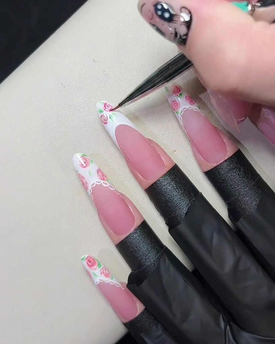 Un pennello liner sottile sfuma gel rosa nel gel bianco umido per creare piccoli motivi floreali.