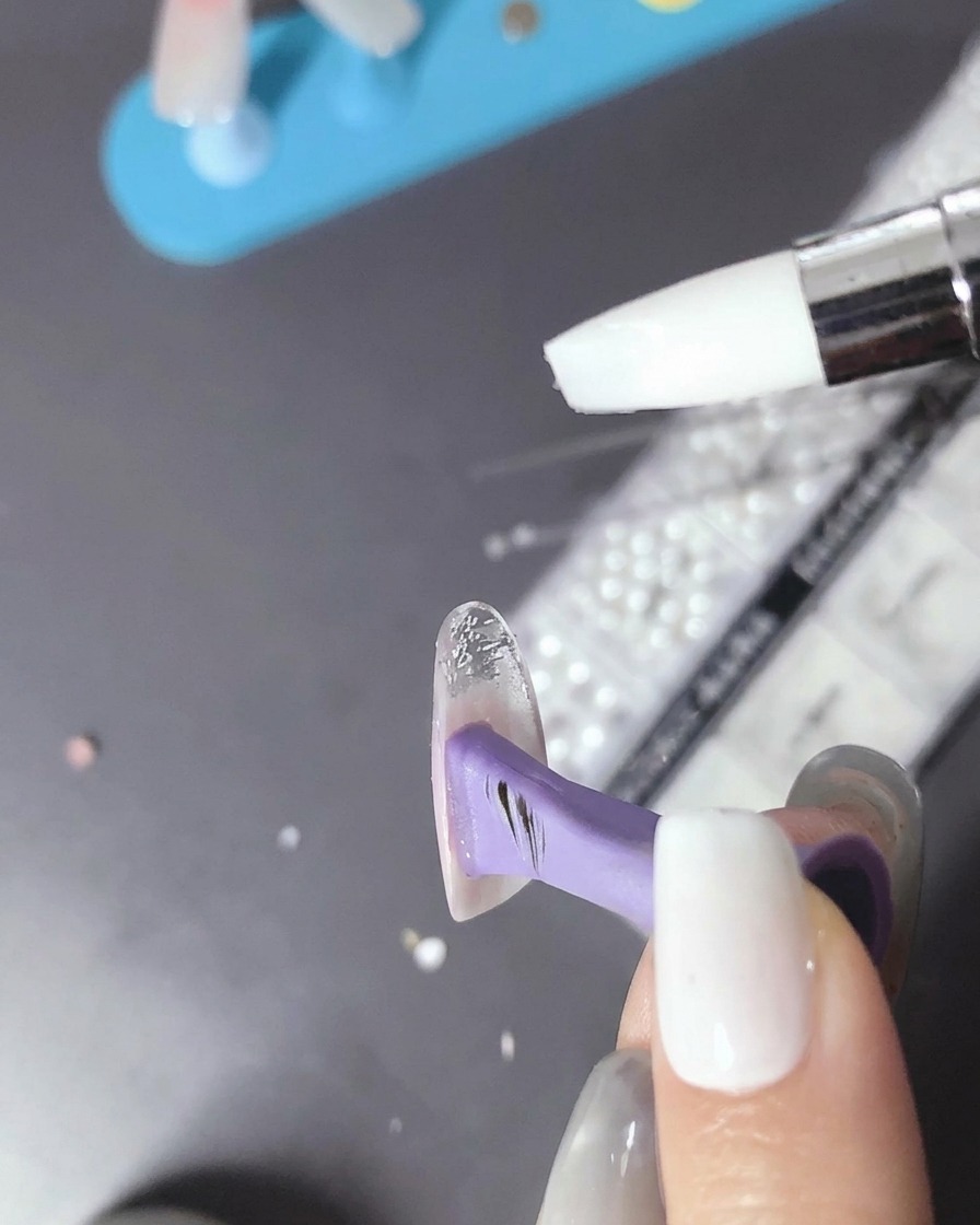 Un pennello che applica una piccola quantità di gel trasparente sullunghia polimerizzata.