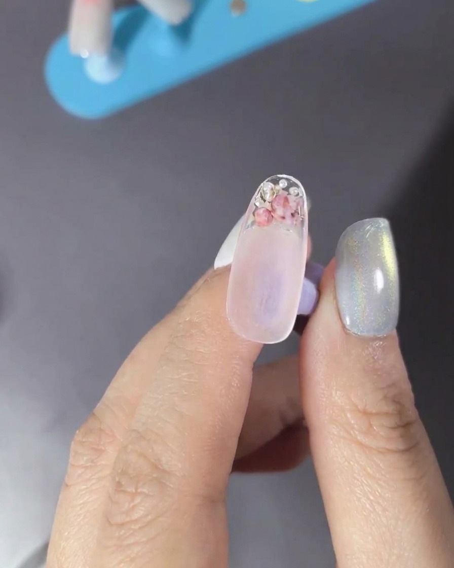 Un pennello che applica un top coat trasparente sopra ununghia decorata.