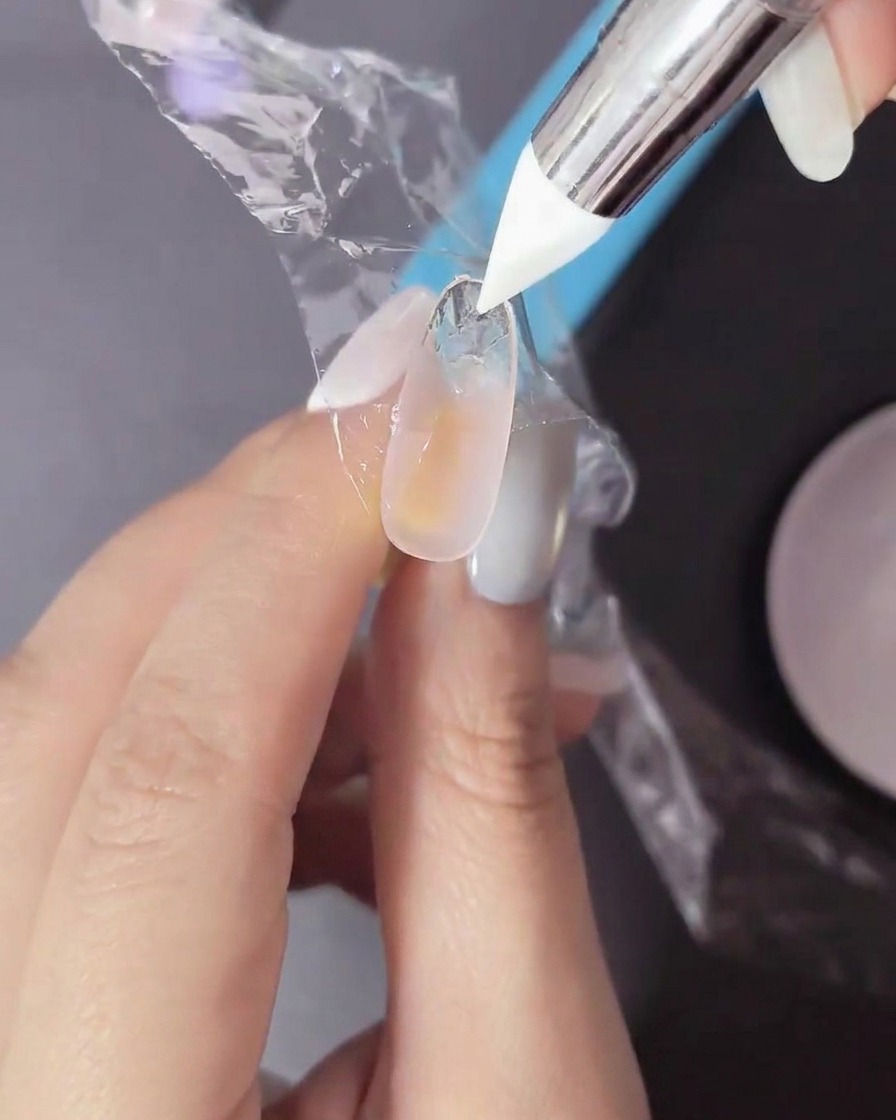 Ununghia con gel non polimerizzato su cui viene premuta una pellicola sottile con uno strumento in silicone.