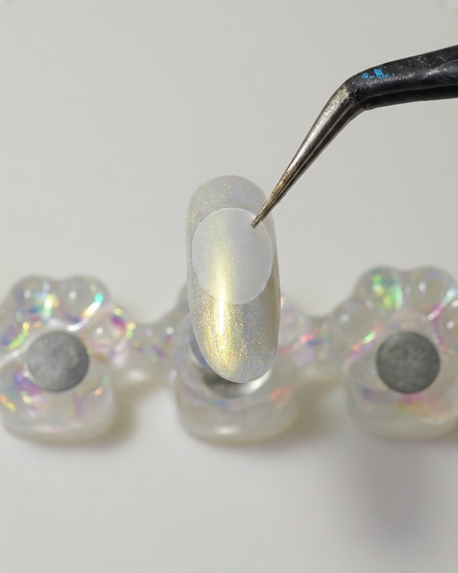 Una spatola in metallo applica una goccia di gel costruttore solido trasparente sulla parte inferiore di un disco di plastica trasparente.