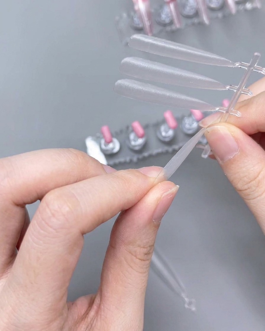 Primo piano di mani che usano una lima per modellare il bordo di una tip in plastica trasparente.