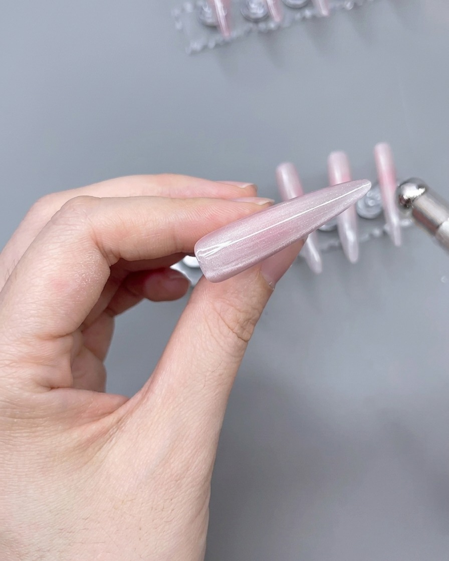 Un magnete posizionato sopra una tip rivestita di gel cat-eye per creare un effetto luminoso.
