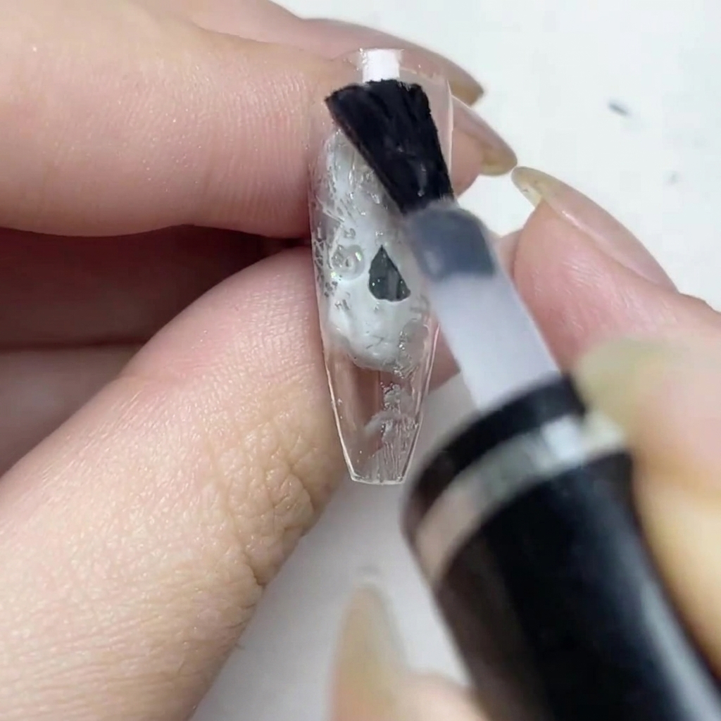 Un pennello applica uno strato di top coat opaco sullunghia con lamina.