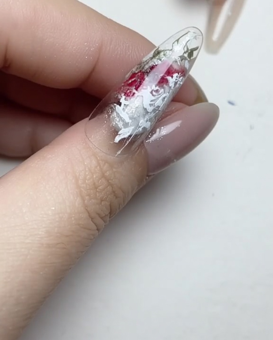 Un pennello a punta sottile applica piccole gocce trasparenti di adesivo gel sulla superficie di ununghia.