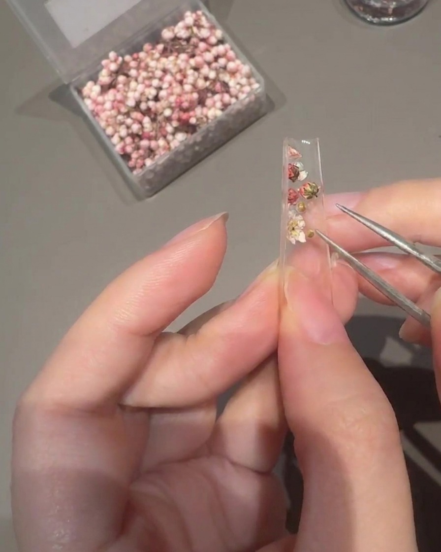 Applicazione di gel costruttore trasparente sopra la tip decorata usando un pennello piatto.