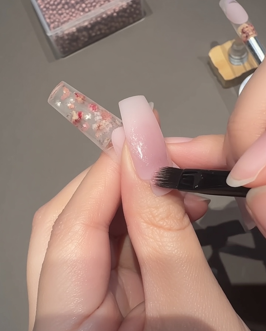 Applicazione di un gel cat-eye magnetico rosa semitrasparente sopra la base.