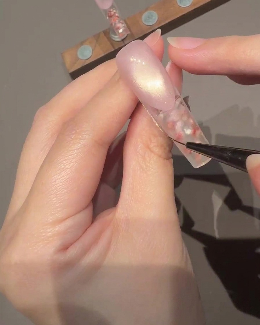 Un pennello che applica un top coat trasparente e lucido sulla superficie dellunghia decorata.