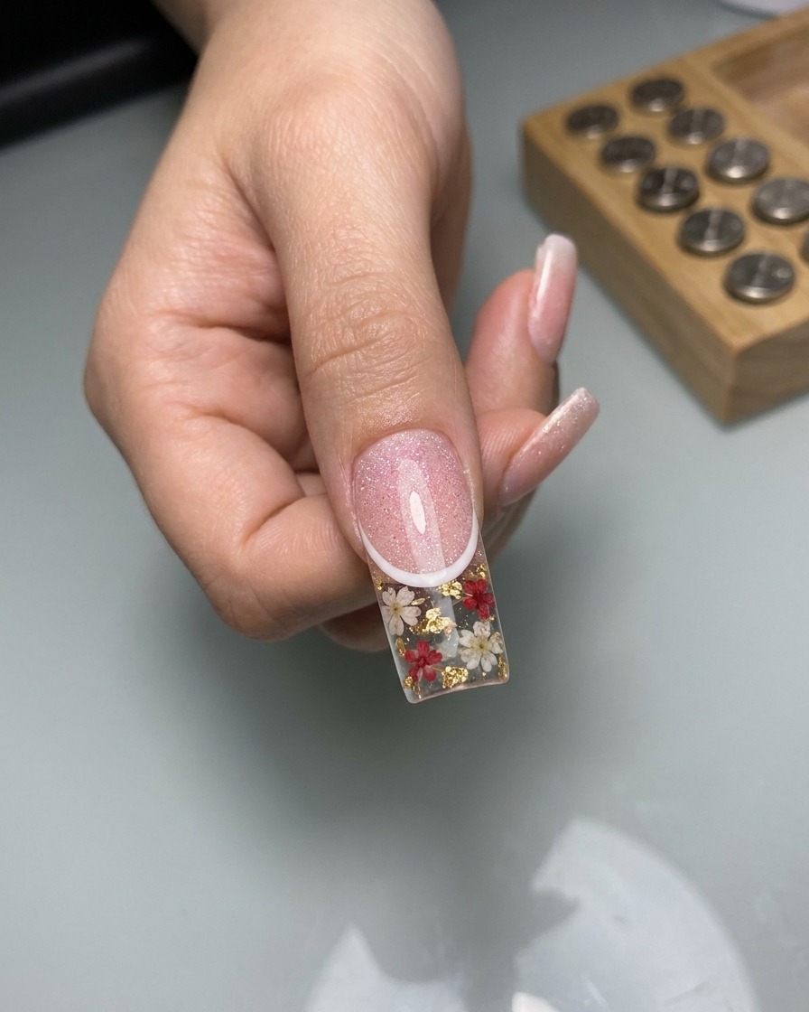 Primo piano che mostra un pennello a punta sottile che disegna linee delicate a motivo pizzo bianco sopra la superficie cat-eye.