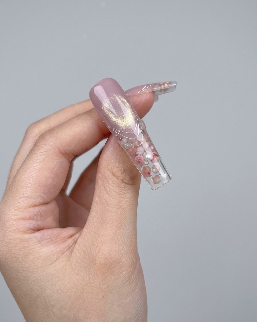 Un paio di pinzette che posizionano un piccolo fiocco di cristallo 3D scintillante su ununghia.