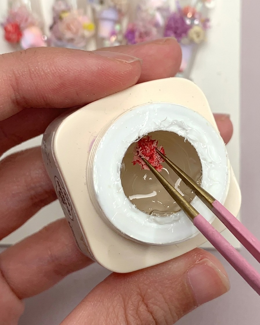 Un pennello che applica una goccia di gel adesivo opaco su una tip trasparente.