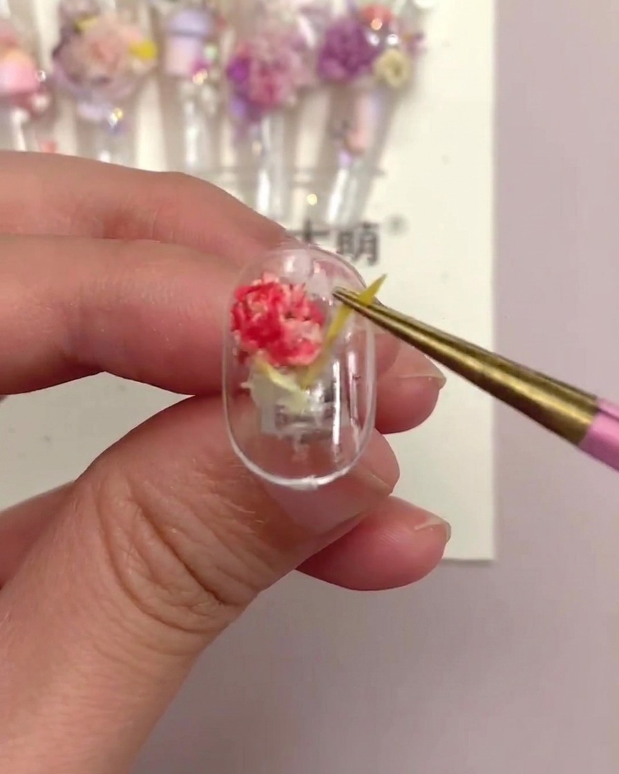 Un paio di pinzette che tirano delicatamente un pezzo di fiore lineare giallo su una tip finita per testarne la sicurezza.