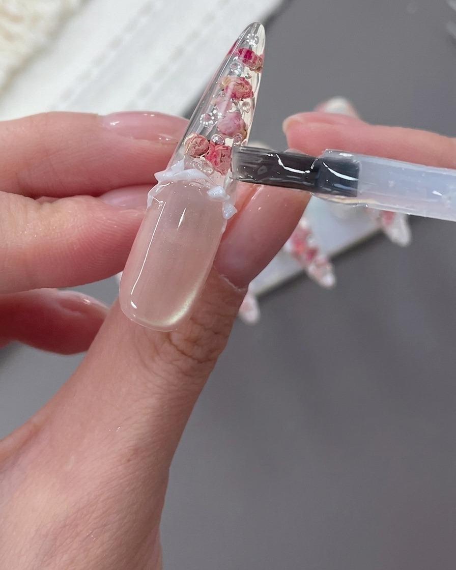 Ununghia decorata con fiocco bianco, perle e strass in fase di finalizzazione.