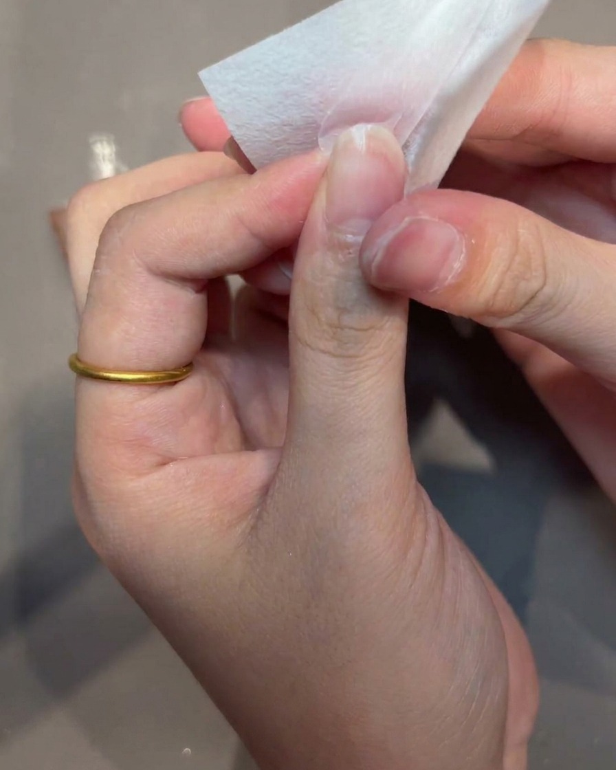 Mano che pulisce la superficie della tip con un pad senza pelucchi.