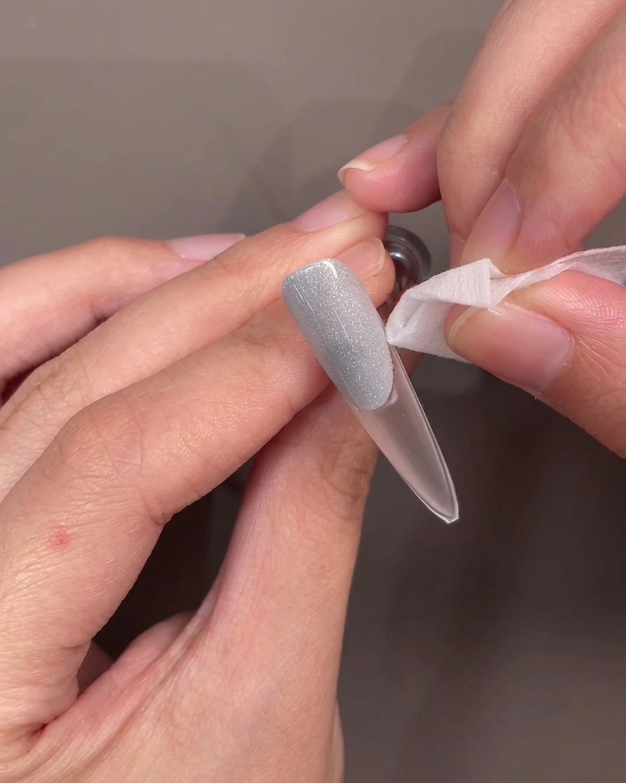 Pinzette che sollevano una guida in silicone dallunghia, rivelando un bordo curvo pulito sul gel blu.