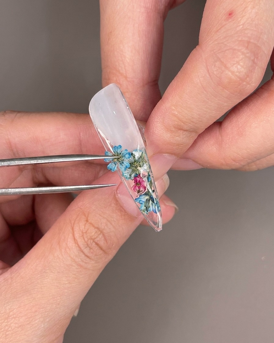 Dettaglio di strass trasparenti posizionati tra i fiori secchi sul retro della punta dellunghia.