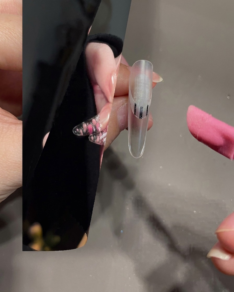 Un pennello per nail art che stende gel bianco sulla punta di ununghia trasparente.
