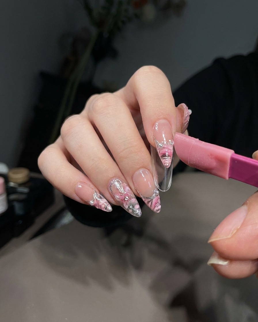 Una pinzetta che solleva con cura un adesivo French dal gel bianco polimerizzato su una tip.