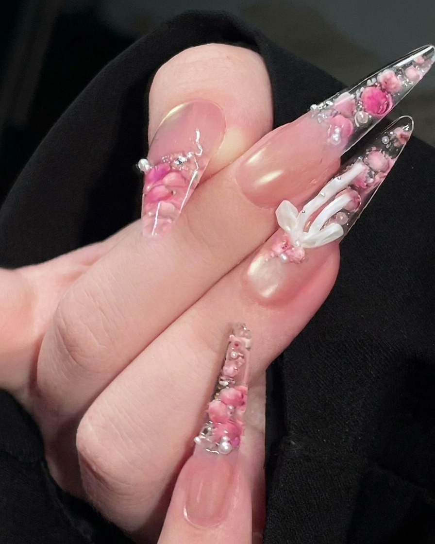 Un pennello che applica un top coat trasparente e lucido sulla superficie del design dellunghia con rosa finito.